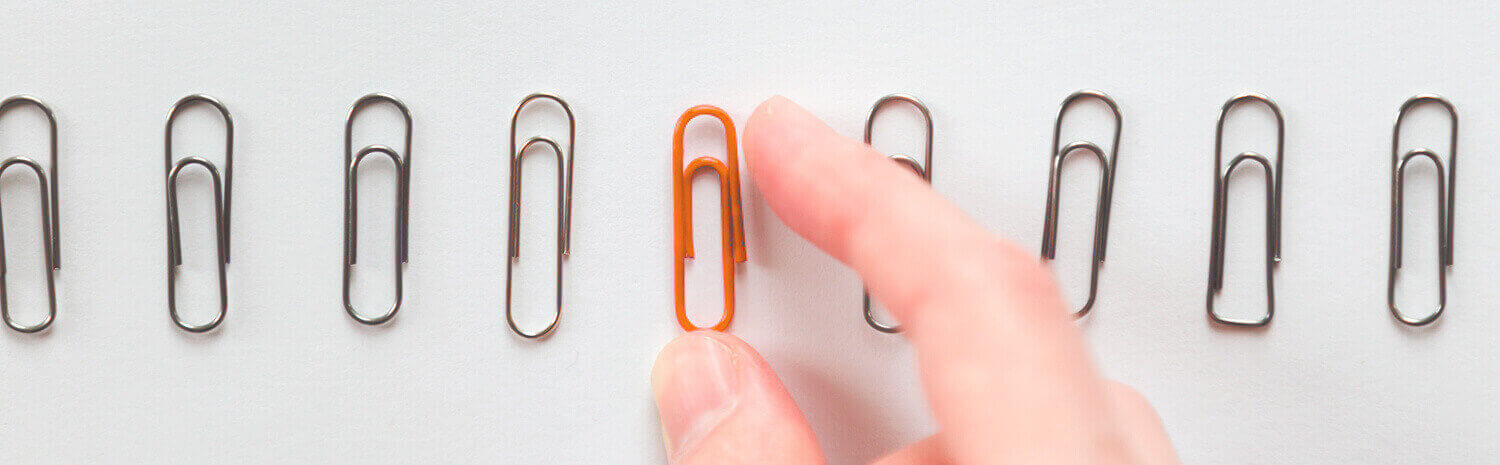 Photo of an orange paperclip between gray paperclips
